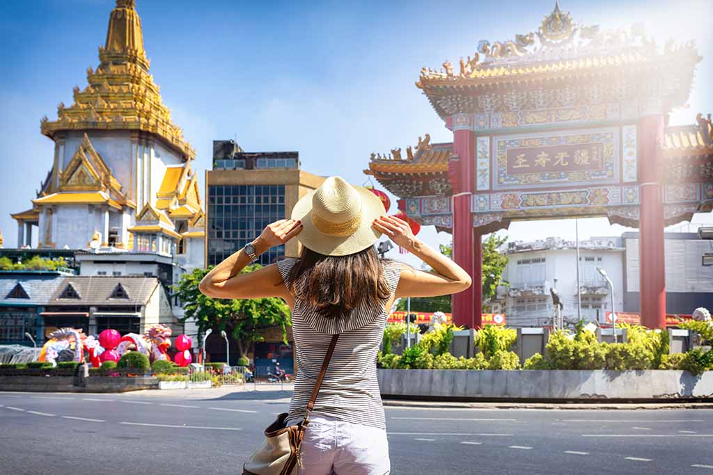 A tourist woman stands in front of the Chinatown Gate at Bangkok